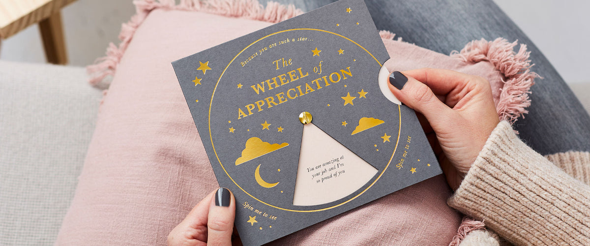 Martha Brook Personalised The Appreciation Reveal Wheel being held on a pink cushion