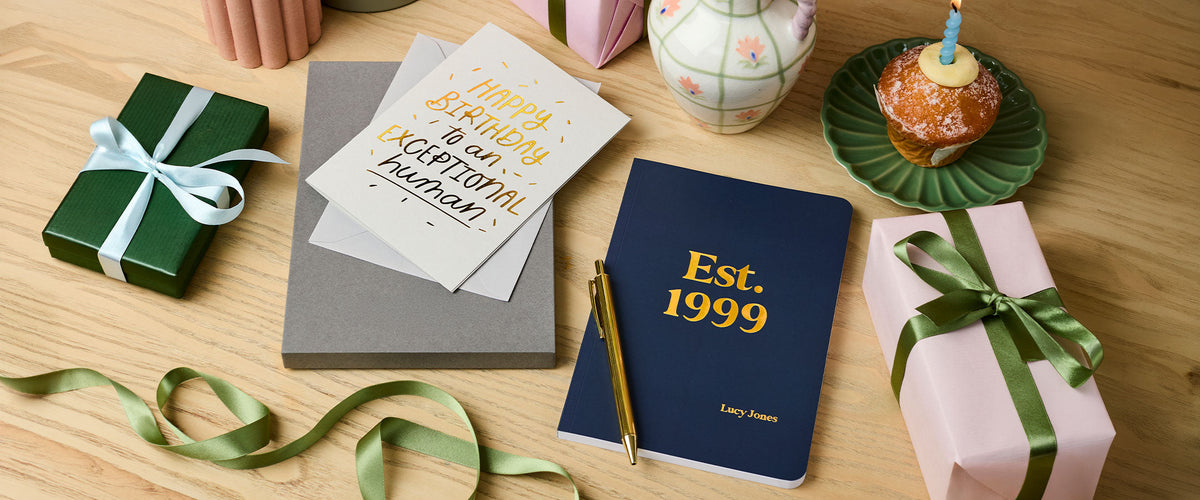 Martha Brook Personalised Any Year Birthday Gift Softback Notebook with Exceptional Human Foil Embossed Birthday Card with wrapped gifts and a cupcake