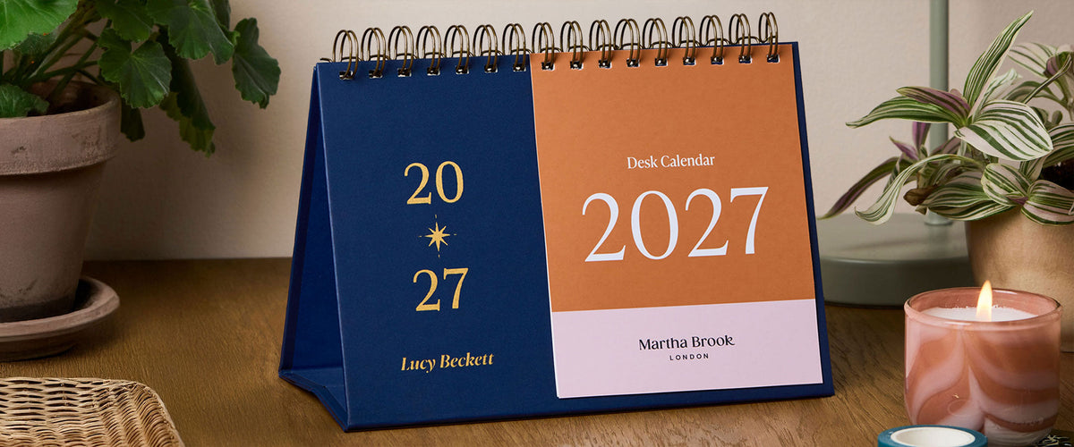 Martha Brook Personalised Sark 2027 Desk Calendar on wooden desk with candle
