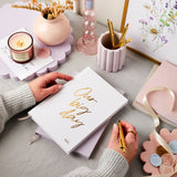 martha brook personalised stationery wedding stationery personalised linen wedding notebooks stacked in ivory white and lilac with candles and flowers