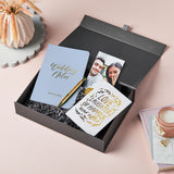 martha brook personalised luxury engagement gift box on a pink background with the box opened up. Inside the box is a wedding notes notebook, a gold pen, a photo holder and an engagement card