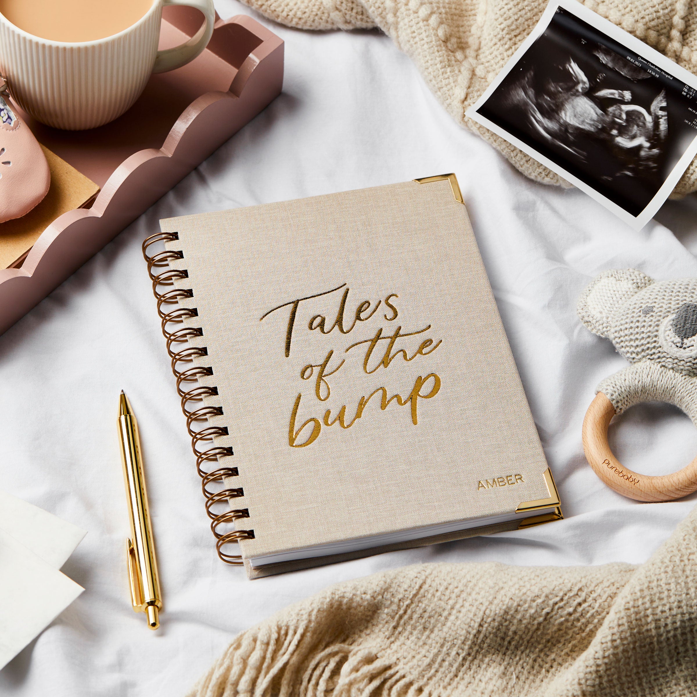 Martha Brook Personalised Pregnancy Journal on a bed with an ultrasound scan, pen and baby items
