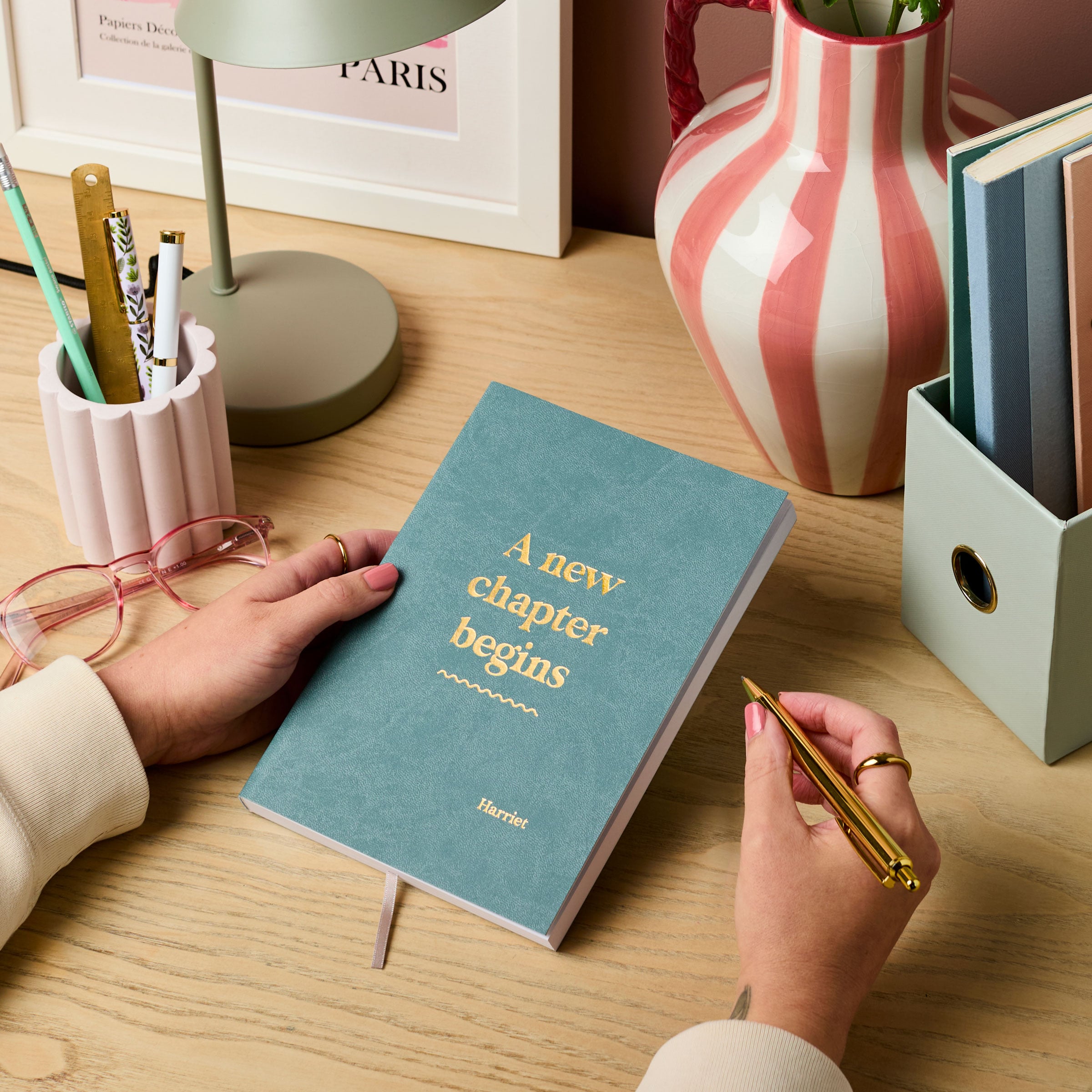 Martha Brook personalised stationery personalised new job gift notebook teal with gold foil on a wooden desk with a pink pen pot, pink striped vase and green lamp
