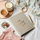 martha brook personalised baby journal and organiser on bed spread with candle and baby grow and baby rattle wide