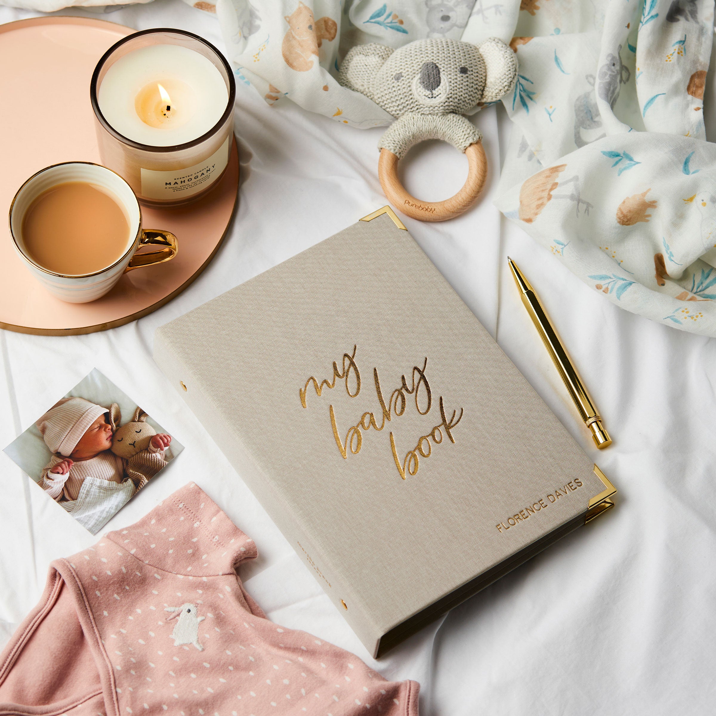 martha brook personalised baby journal and organiser on bed spread with candle and baby grow and baby rattle wide