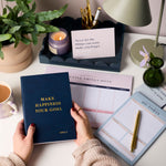 martha brook personalised stationery happiness planning stationery bundle notebook being held up on desk with rest of bundle