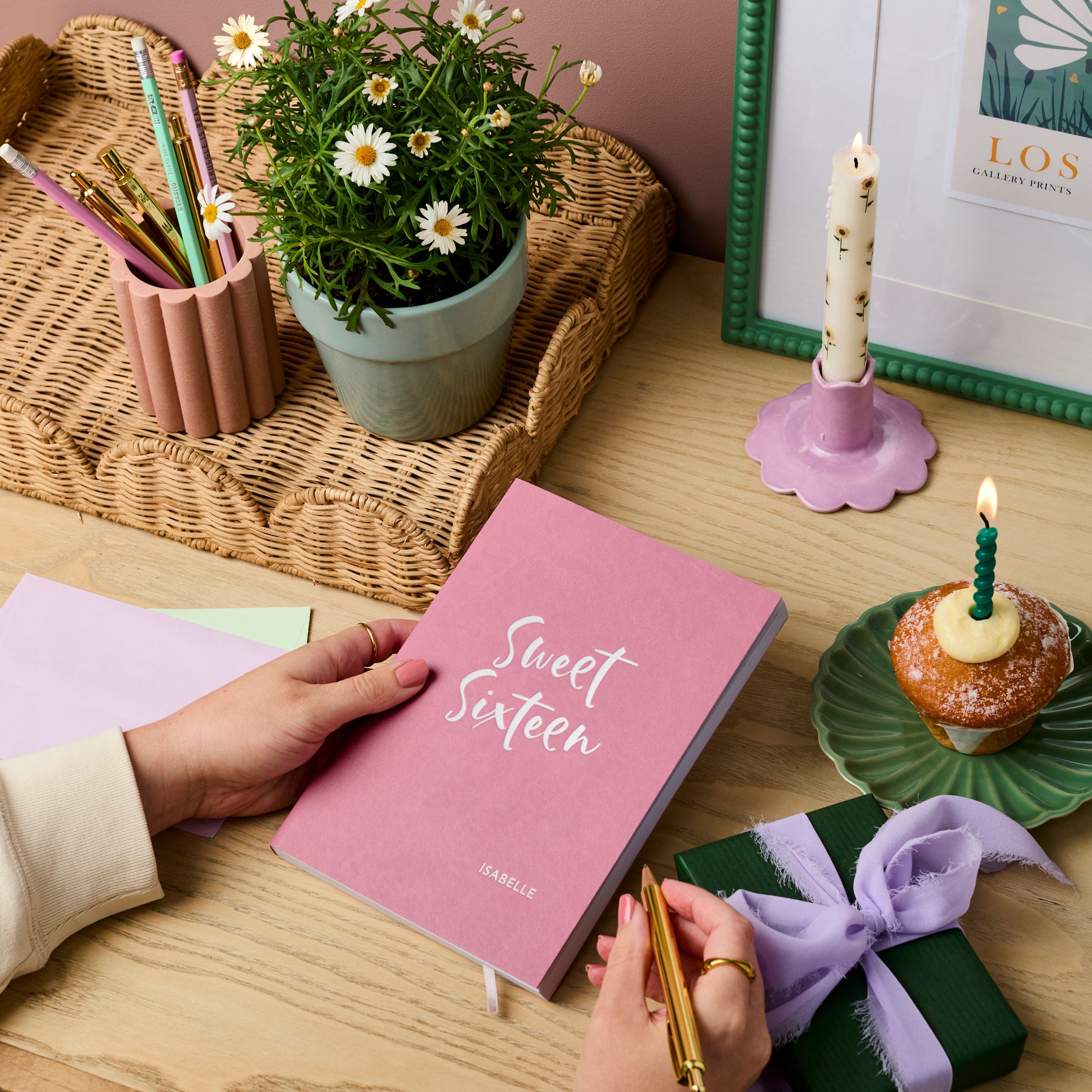 martha brook personalised stationery personalised 16th birthday gift notebook main image pink vegan leather notebook on a wooden desk. The cover of the notebook reads 'sweet sixteen' in silver foil