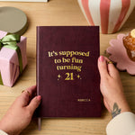 martha brook personalised stationery personalised 21st birthday gift softback notebook main image a dark red vegan leather notebook reads 'it's supposed to be fun turning 21' in gold foil