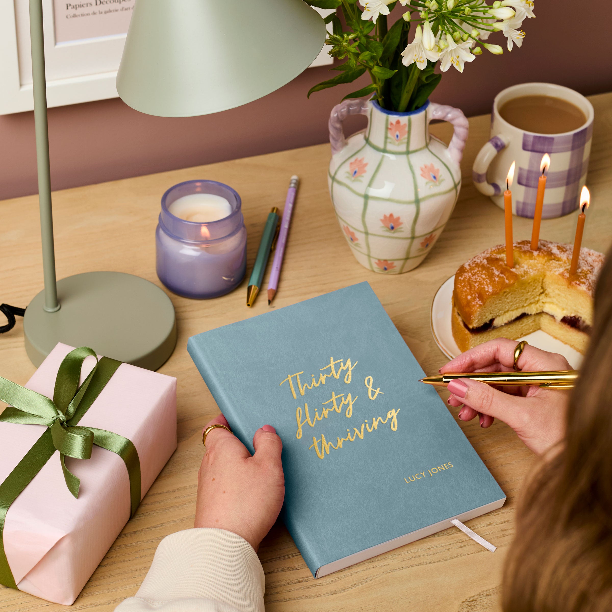 martha brook personalised stationery personalised 30th birthday gift notebook. A teal vegan leather notebook on a wooden desk reads 'thirty, flirty and thriving' on the cover in gold foil