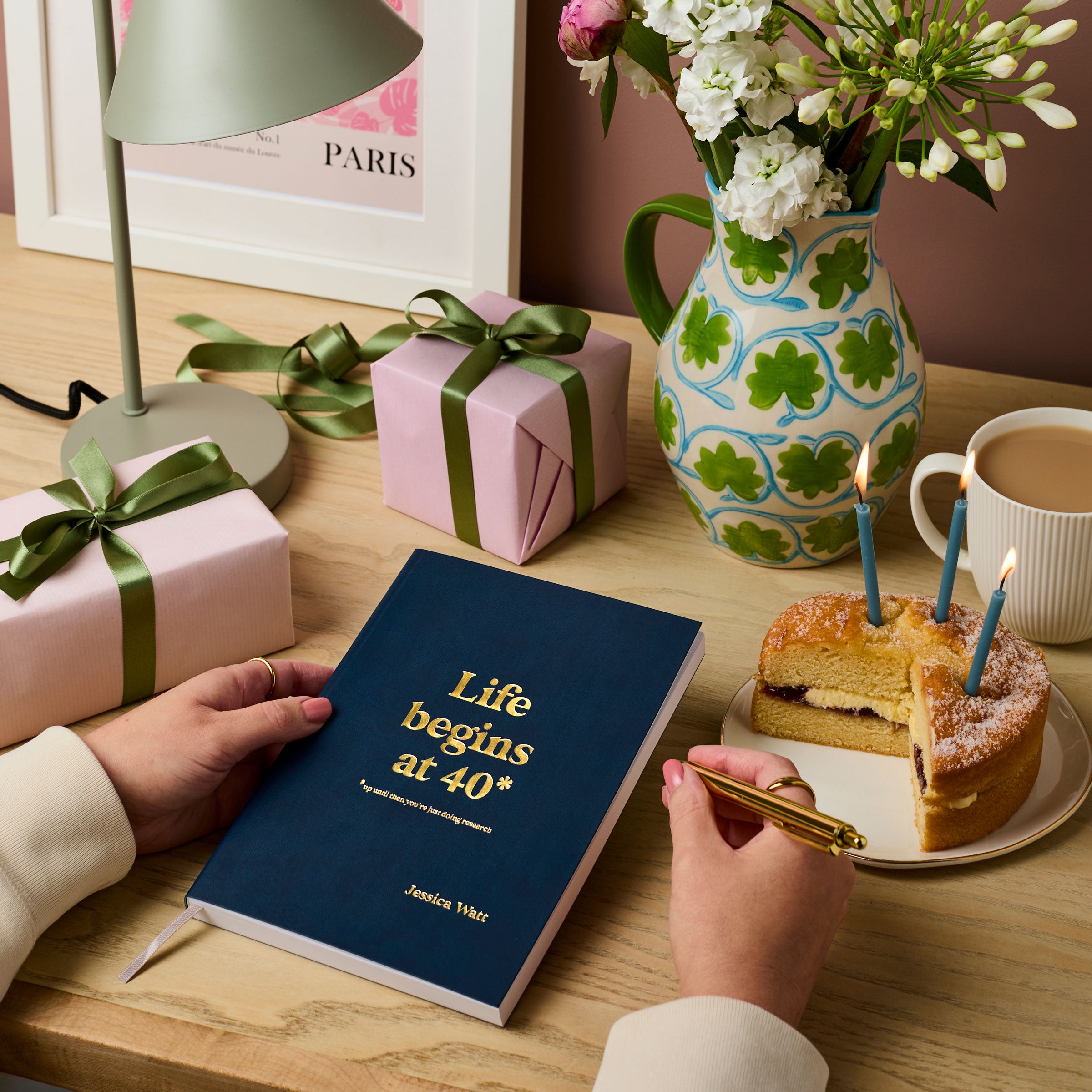 martha brook personalised stationery personalised 40th birthday gift notebook navy blue notebook on a wooden desk. The notebook reads 'life beings at 40. Up until then you're just doing research' in gold foil on the cover