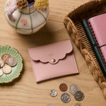 martha brook personalised stationery personalised mini scallop pouch in pink on a wooden desk with a rattan scalloped tray and hand painted dried flower vase