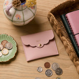 martha brook personalised stationery personalised mini scallop pouch in pink on a wooden desk with a rattan scalloped tray and hand painted dried flower vase