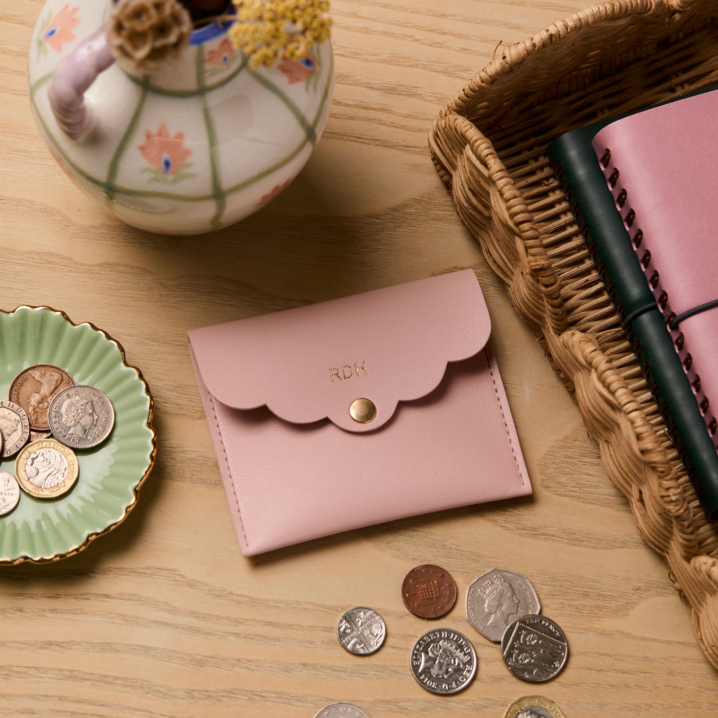 martha brook personalised stationery personalised mini scallop pouch in pink on a wooden desk with a rattan scalloped tray and hand painted dried flower vase