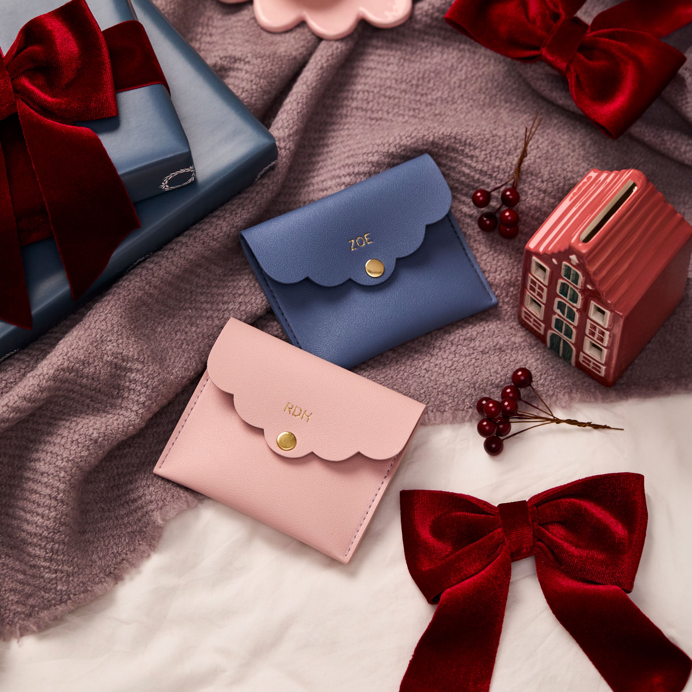 martha brook personalised stationery personalised mini scallop pouch on a dusty purple blanket with deep red velvet ribbons and a painted ceramic house