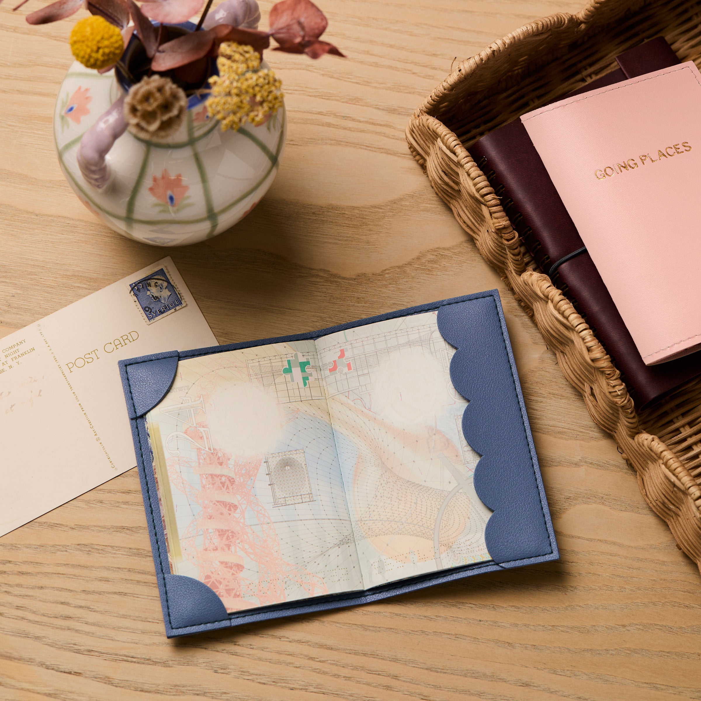 martha brook personalised stationery personalised passport holder open on a wooden desk with dried flowers in a vase and a postcard