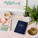 martha brook personalised stationery personalised brilliant 2026 weekly diary navy diary stacked on top of pebble grey hardback diary on a pink desk with cup of tea