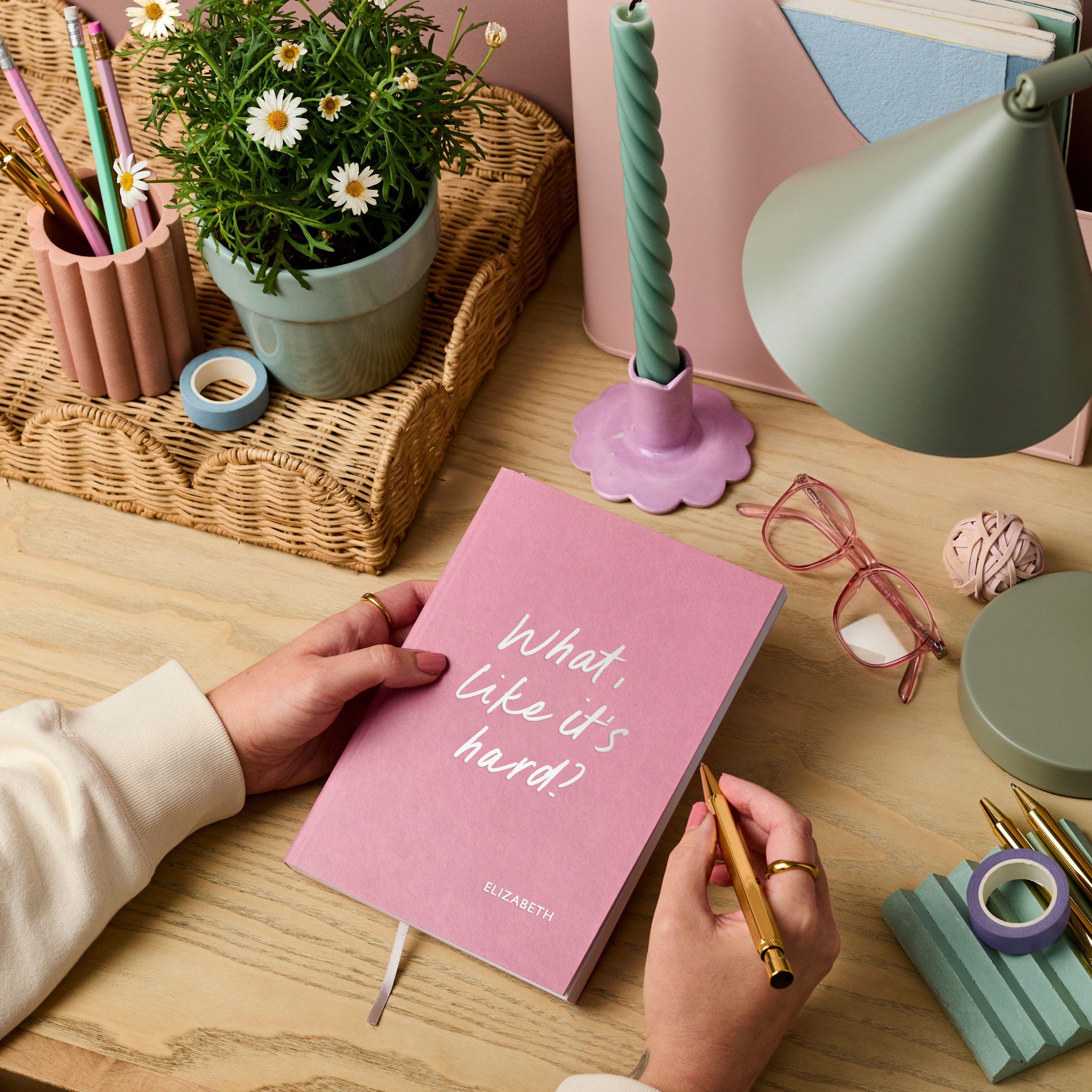martha brook personalised stationery personalised university gift softback notebook pink vegan leather notebook on a wooden desk. The notebook reads 'what, like it's hard?' on the cover in silver foil