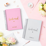 martha brook personalised stationery script bridesmaid notebook in pebble grey on a table next to matching script bridesmaid notebook in rose pink