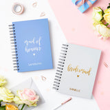 martha brook personalised stationery script maid of honour notebook in sky blue on a table with matching bridesmaid script notebook in pebble grey