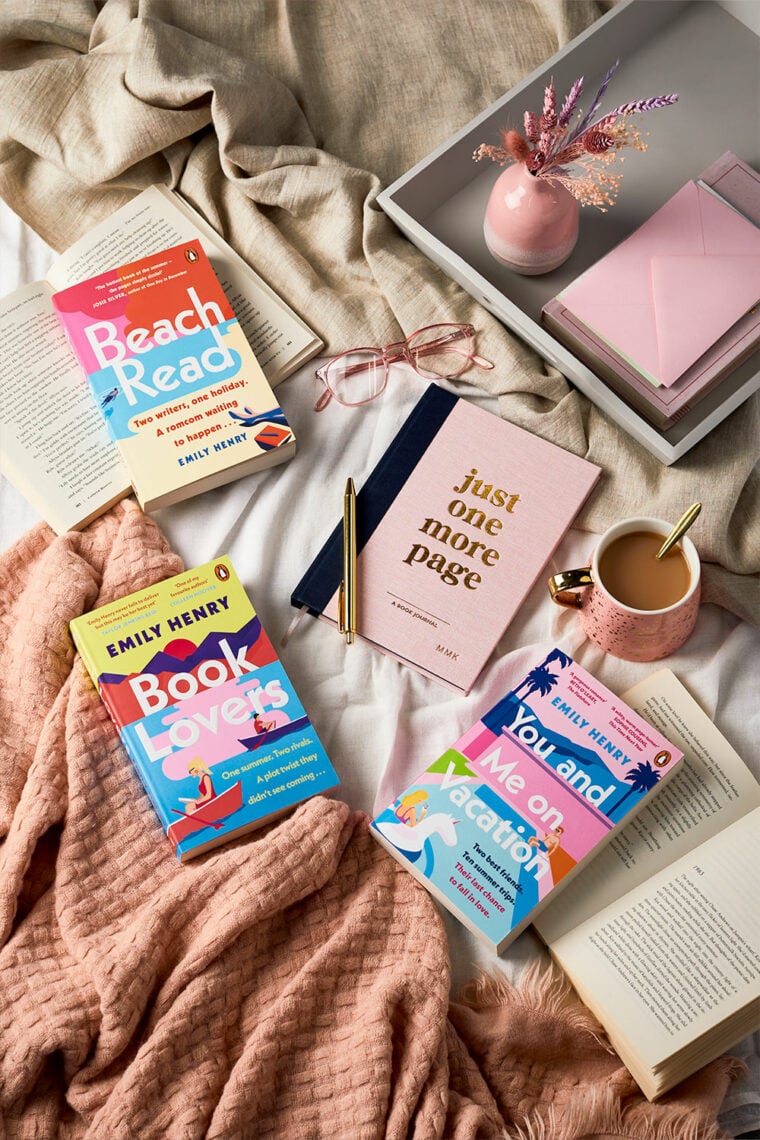 martha brook blog post a review of happy place by emily henry all of her previous books on a bed with a blanket and a martha brook book journal