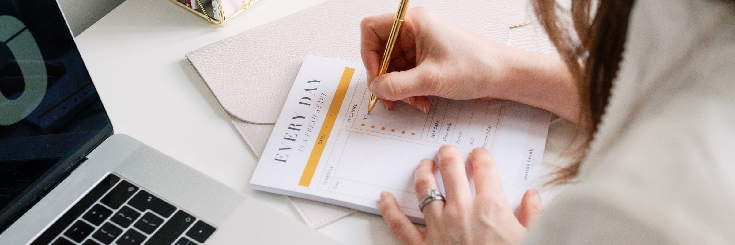 Martha Brook blog 10 favourite productivity methods to boost your focus person writing on desk pad with laptop open