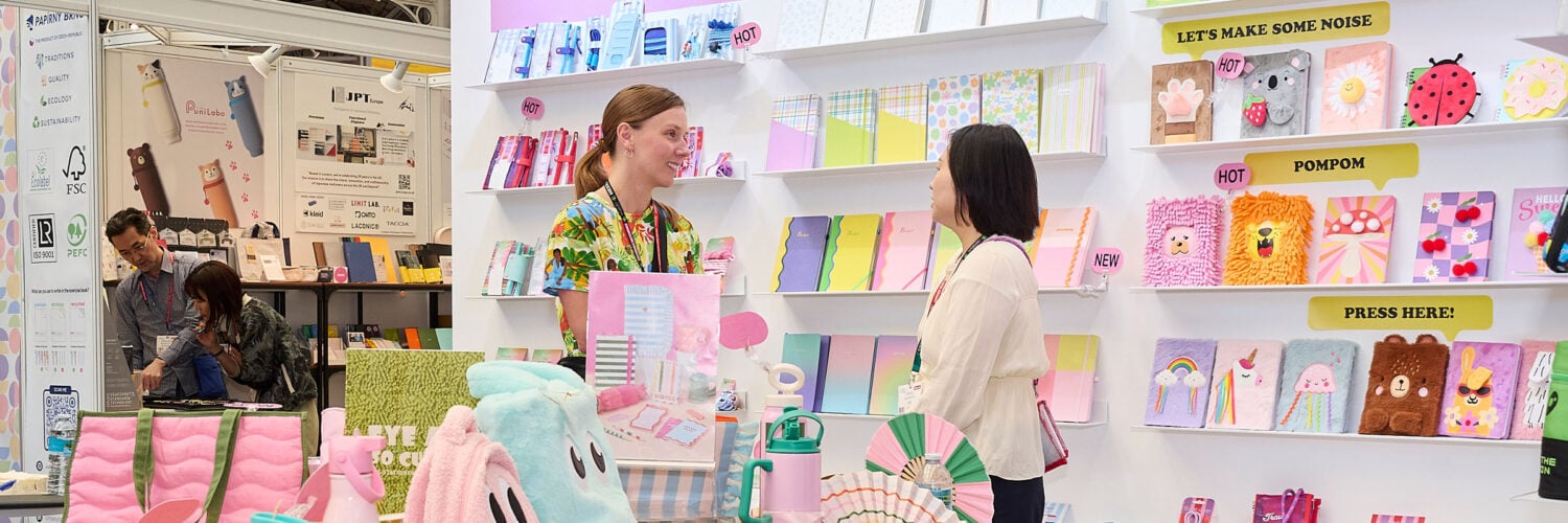 Martha Brook personalised stationery the london stationery show 2025 two women having a conversation stood in front of a wall of colourful notebooks