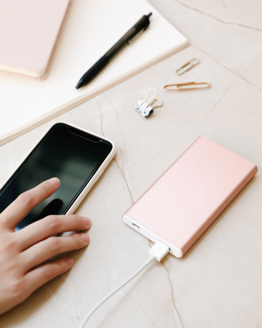 martha brook personalised stationery blog 15 things to take on holiday that you’ll wish you’d thought of sooner power bank. Person harging their phone using a pink portable power bank on a desk