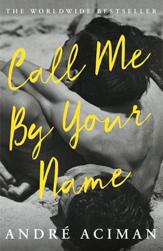 Martha Brook personalised stationery blog 20 best summer reads from old classics to new releases. Call me by your name by andre aciman. The background of the book cover is a black and white photograph of the backs of two men who look to be hugging, sunbathing. The title of the book and the author name are in big yellow hand-written script in front of the image.