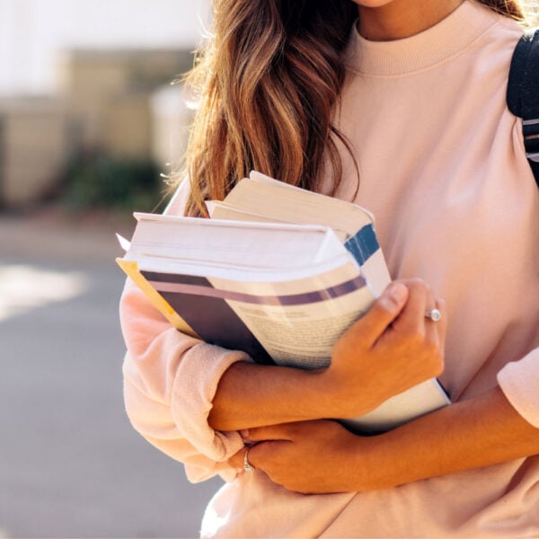 Martha Brook personalised stationery blog Our university essentials and top tips if you’re heading off to study this year woman in pink jumper holding stack of books