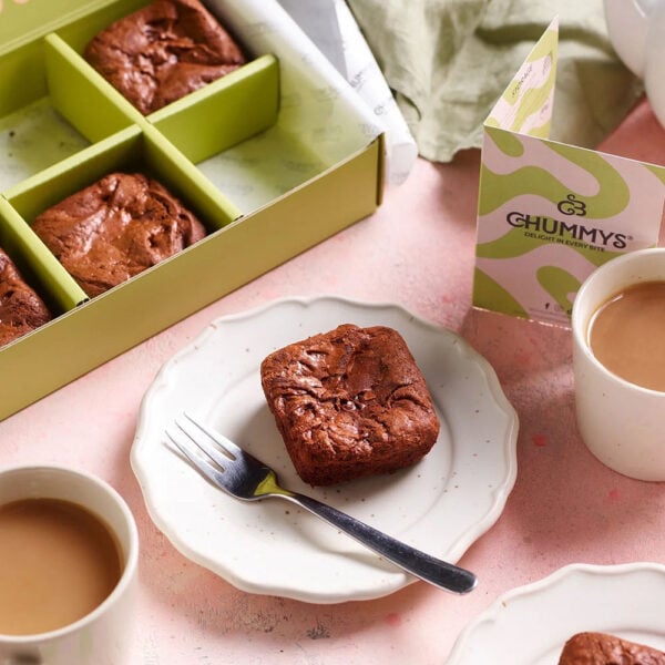 Martha Brook personalised stationery blog 10 ideas for what to get the person who has everything chummy bakery brownie box. A brownie on a white plate with a small dessert fork next to it. There is an open box of brownies behind, and two cups of tea either side.