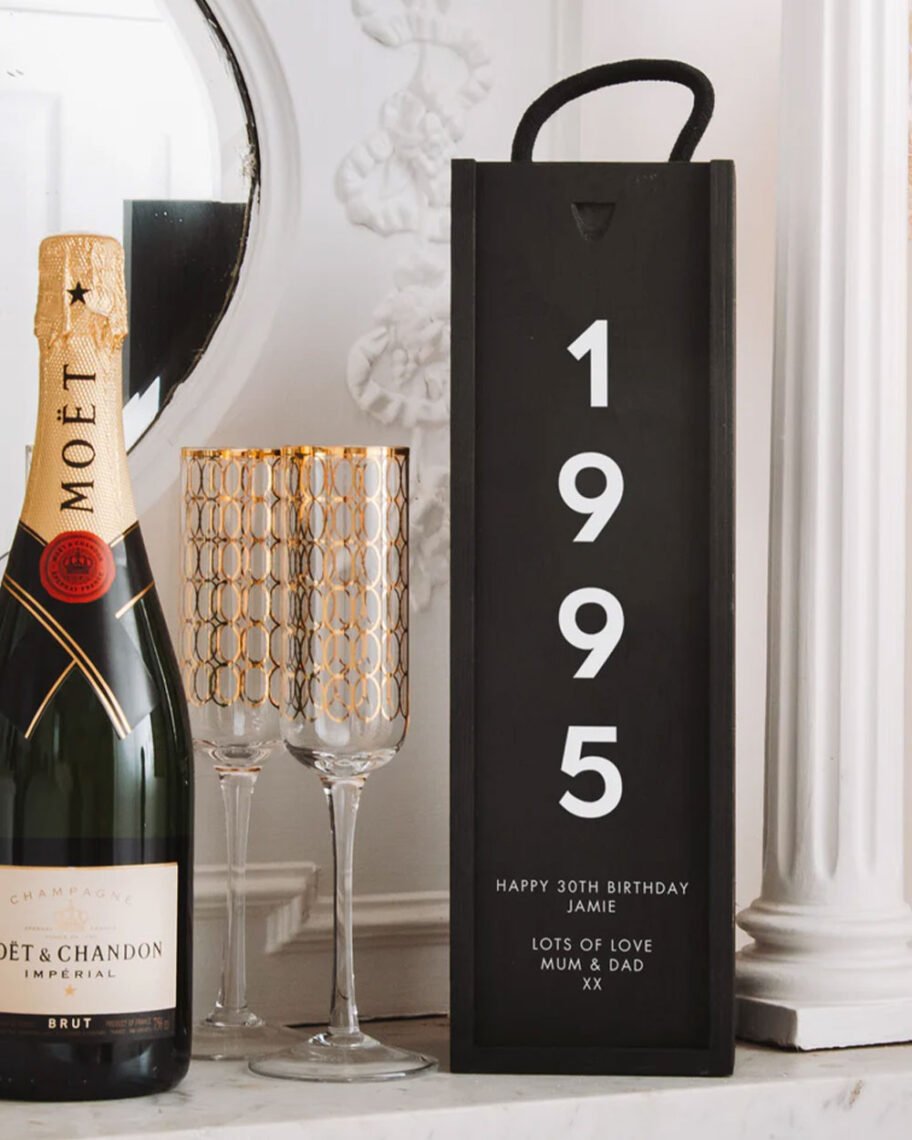 martha brook personalised stationery blog 10 unique birth year personalised birthday gifts stag design personalised bottle box gift set. A black wooden bottle box stands upright on a side. The box reads '1995' in white text. Next to it is an unopened bottle of champagne and two flutes.