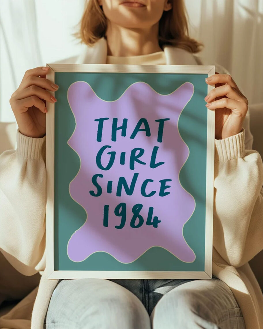 martha brook personalised stationery blog 10 unique birth year personalised birthday gifts tulastra studio personalised birthday print. A gift sat on a chair holding a print in a fram. The print has a purple background and a green squiggle border, with dark blue type that reads 'that girl since 1984'.