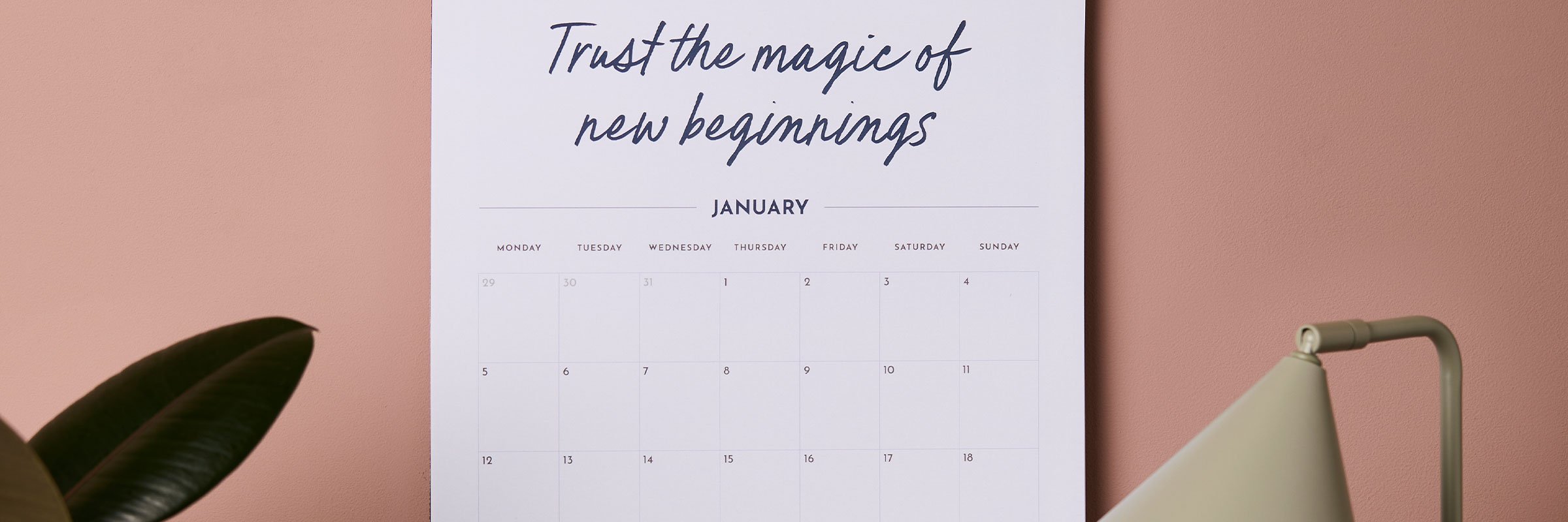 martha brook wall calendars open on january hung up on pink wall with plants next to